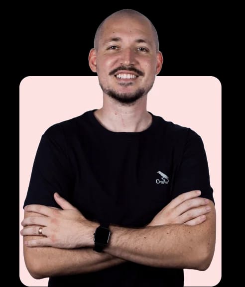 Homem de camiseta preta e braços cruzados sorrindo