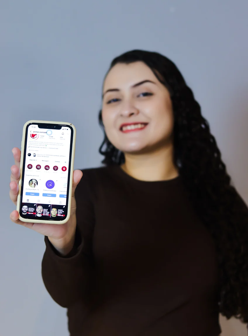 mulher sentada na poltrona de frente com microfone e sorrindo